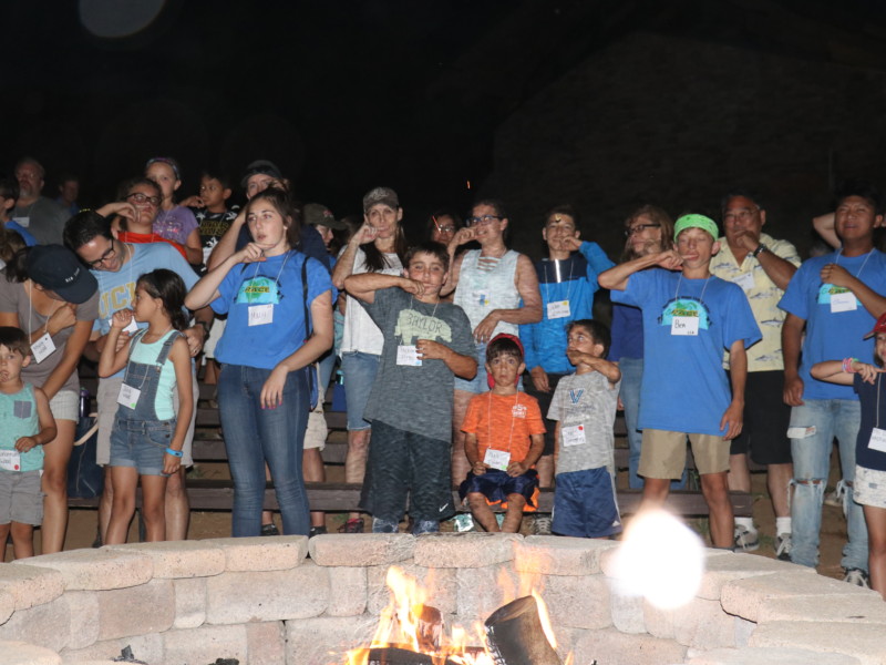 Families singing camp songs around the firepit during Family Camp