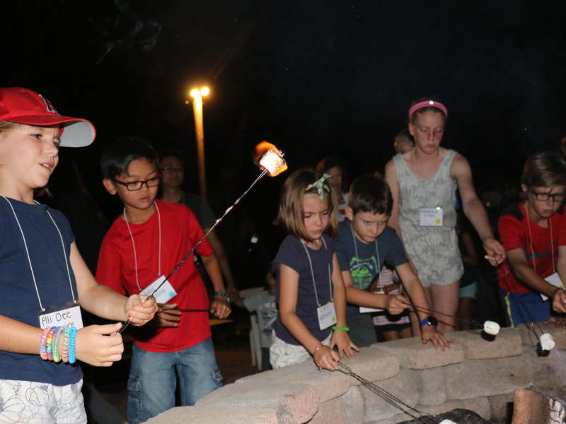 Children roasting marshmallows in firepit during Family Camp