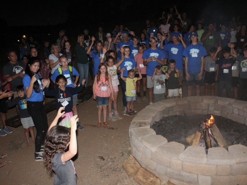 Families gathered around firepit for a sing along