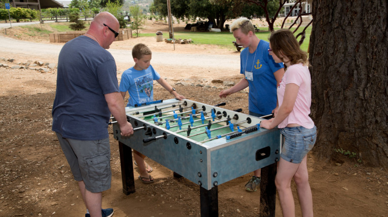 Family playing foosball outside during Special Needs family Camp