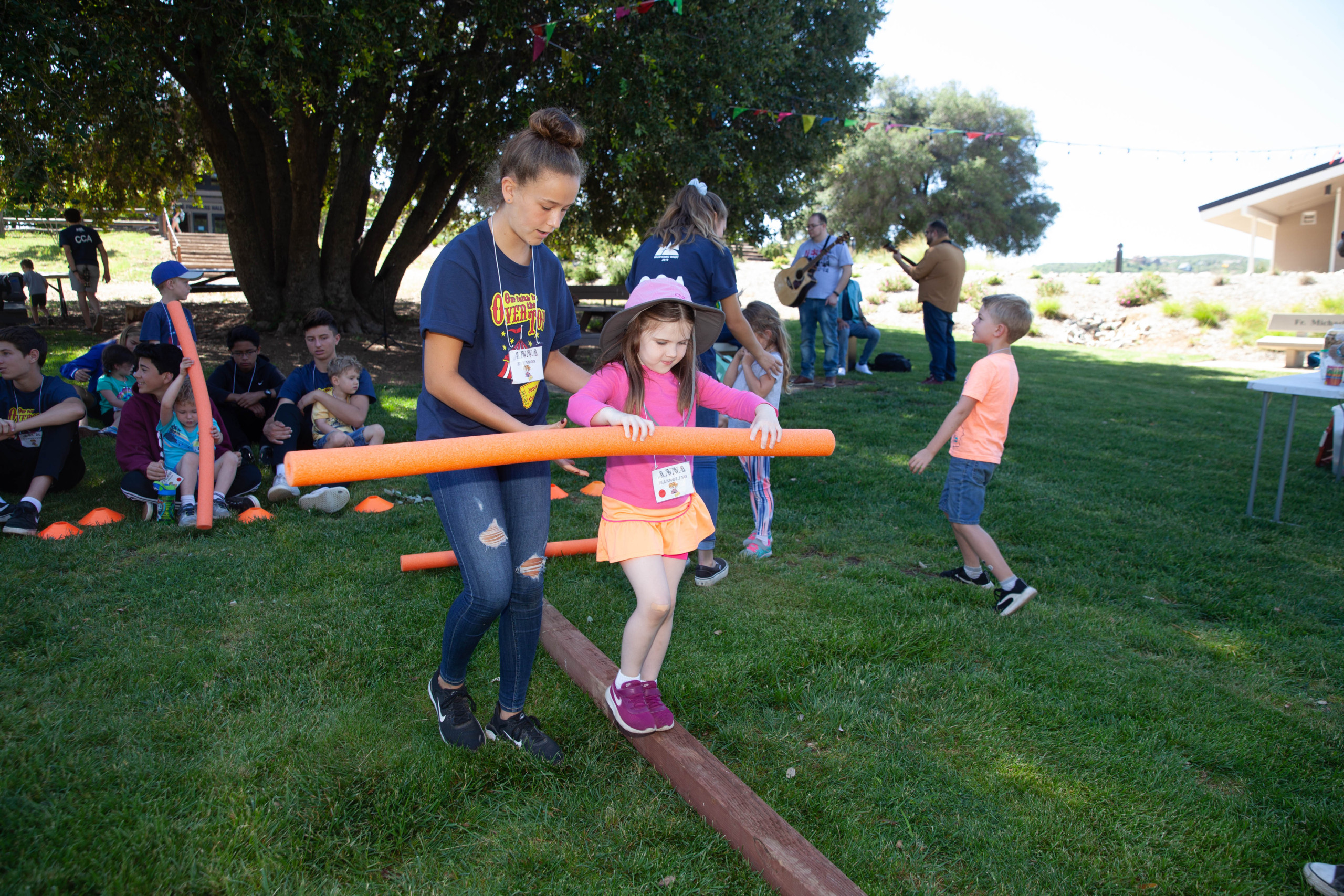 Girl and CCA on balance beam meadow game during Family Camp