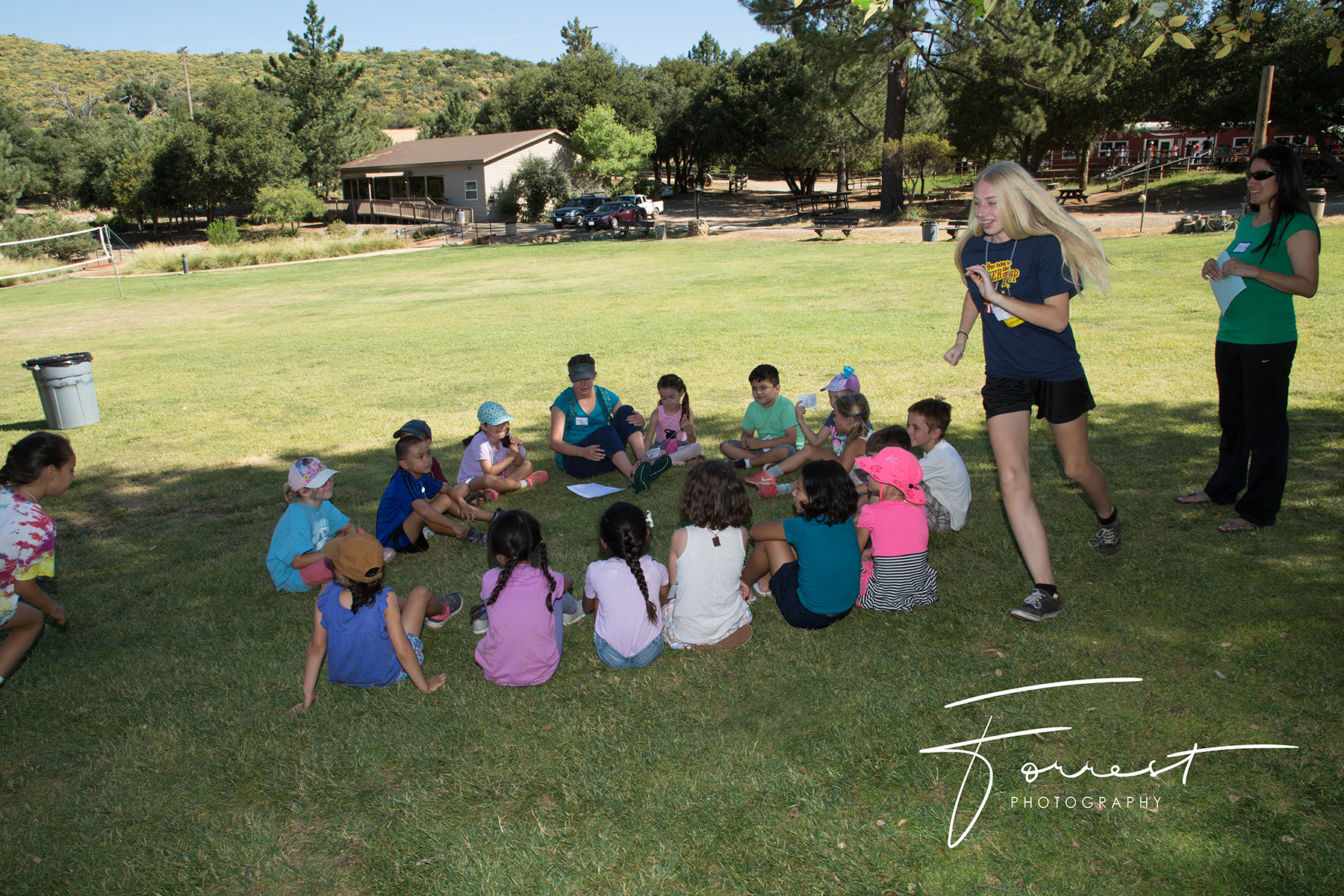 Kids sitting in a circle for a meadow game during Family Camp