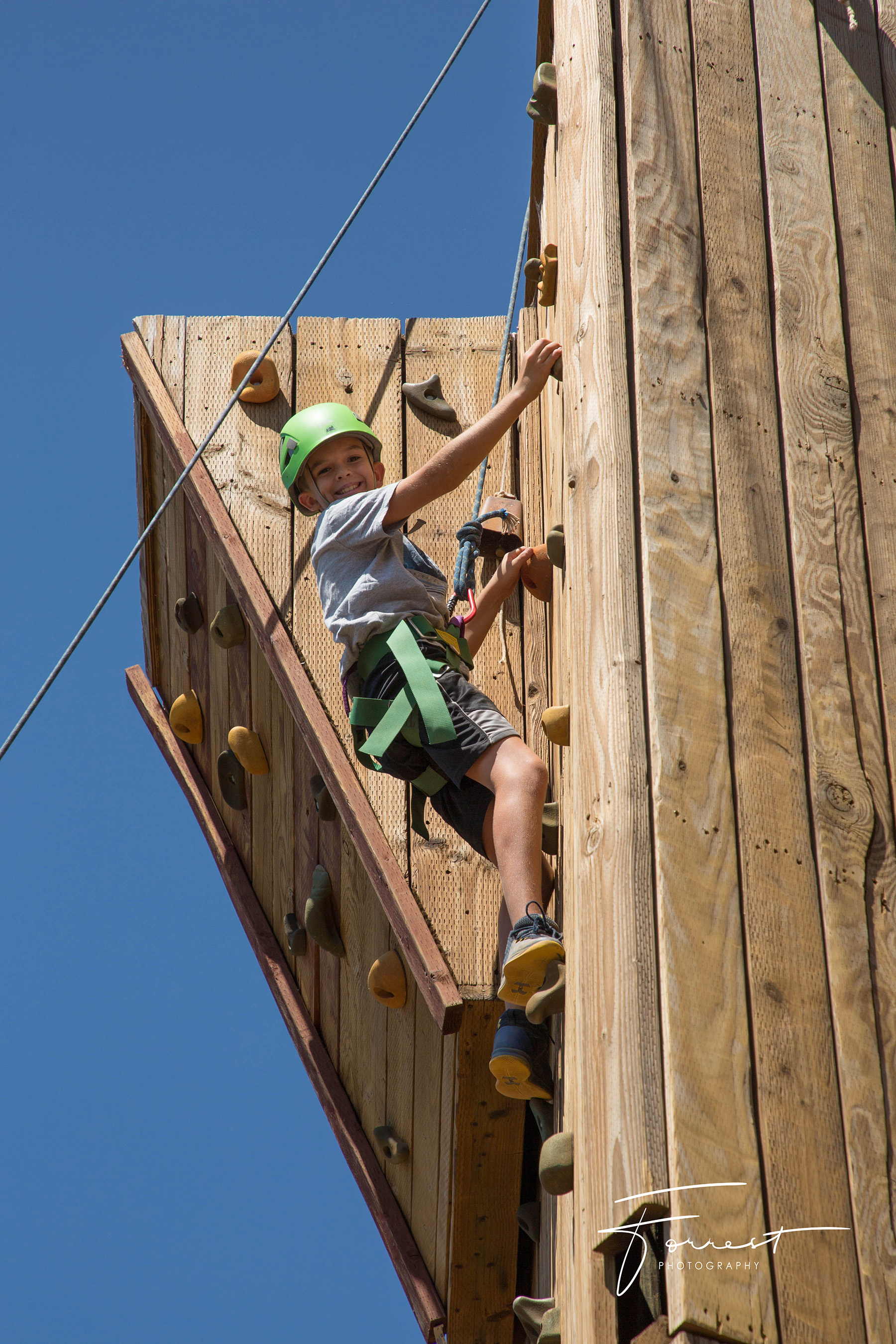 Boy at top of climbing wall during Family Camp