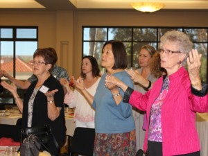 Women holding hands during praise and worship at the Women's Retreat