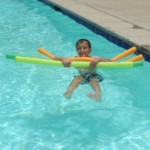 Boy with pool toy noodles in water