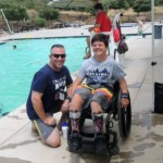 TAPS adult volunteer with child in wheelchair at pool