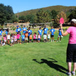 Kids, CCAs and Women's Auxiliary voluntter on meadow playing games