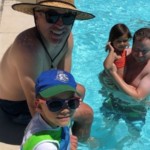 Dad and child sitting on edge of swimming pool