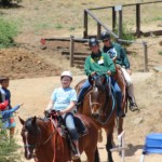 Family on horses walking through camp