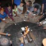 Kids and adults roasting marshmallows at firepit