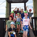 Children in helmets waiting on zip line steps